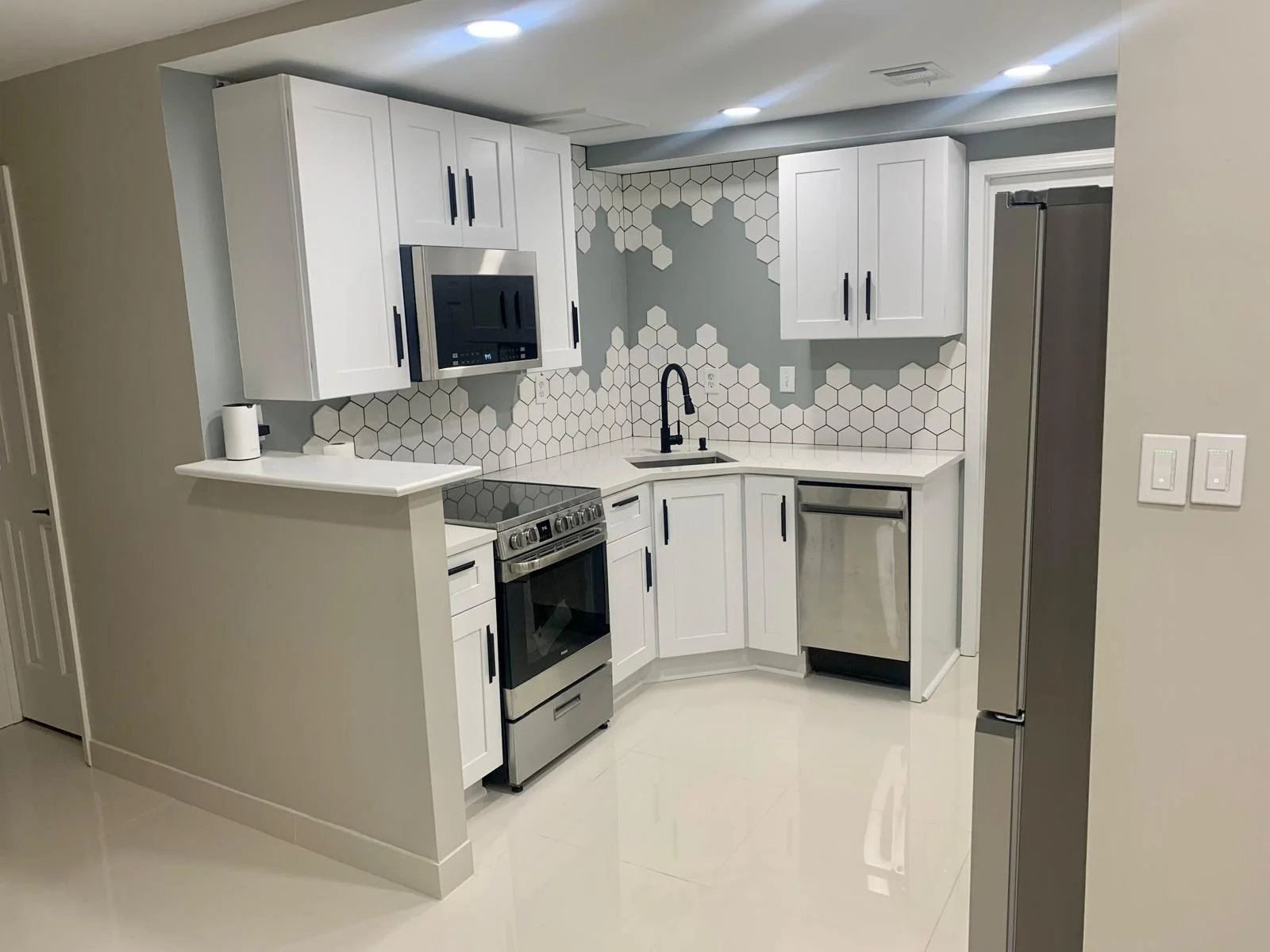 Kitchen after remodel — modern white cabinets with hexagon tile backsplash